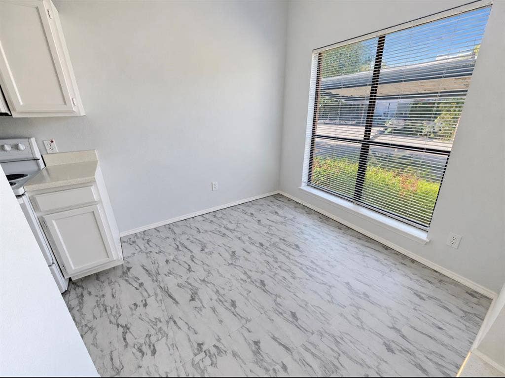 7126 Holly Hill Drive, #108, Dallas, TX 75231 White cabinetry with a light-toned countertop, a window with horizontal blinds, and patterned flooring