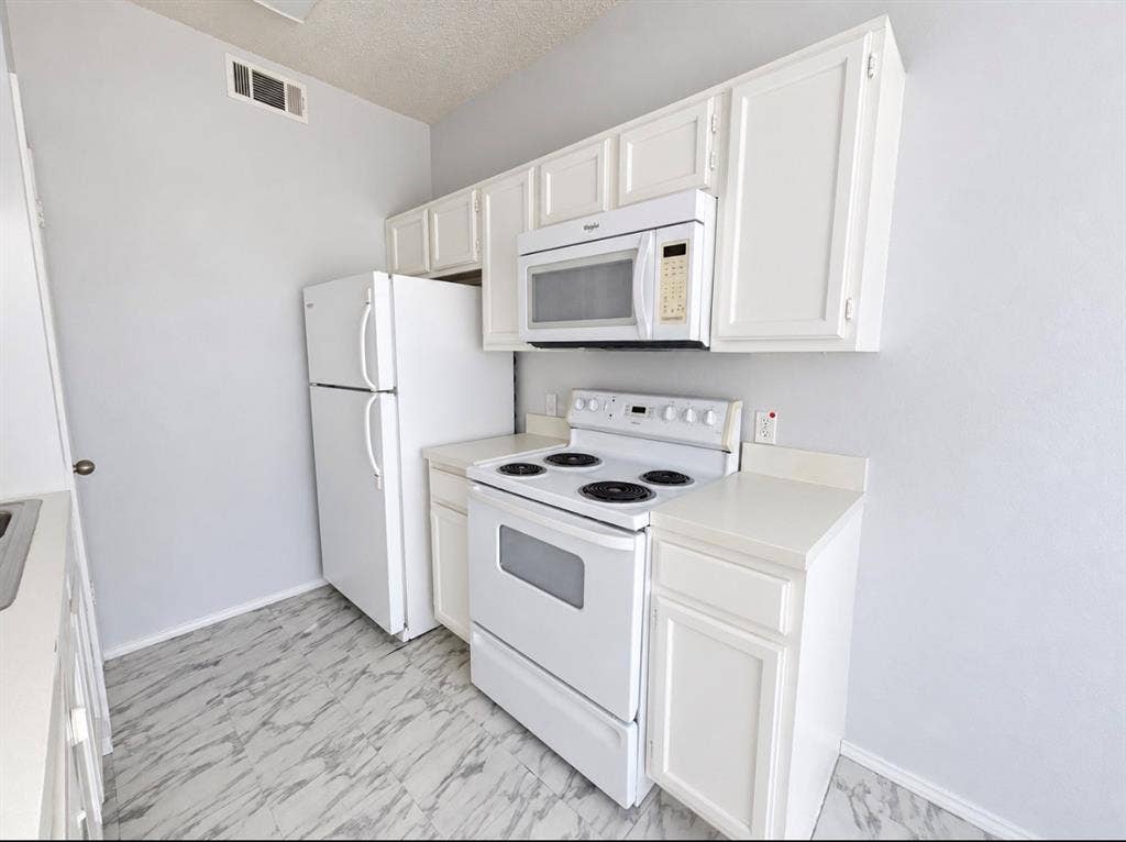 7126 Holly Hill Drive, #108, Dallas, TX 75231 White cabinetry, white appliances, white countertops, white walls, and marble-look flooring