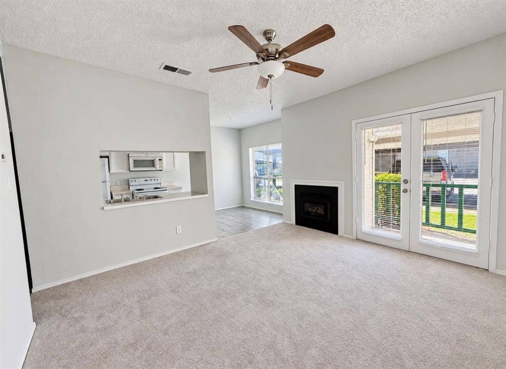 7126 Holly Hill Drive, #108, Dallas, TX 75231 Carpeted living area with a ceiling fan, fireplace, and glass patio doors