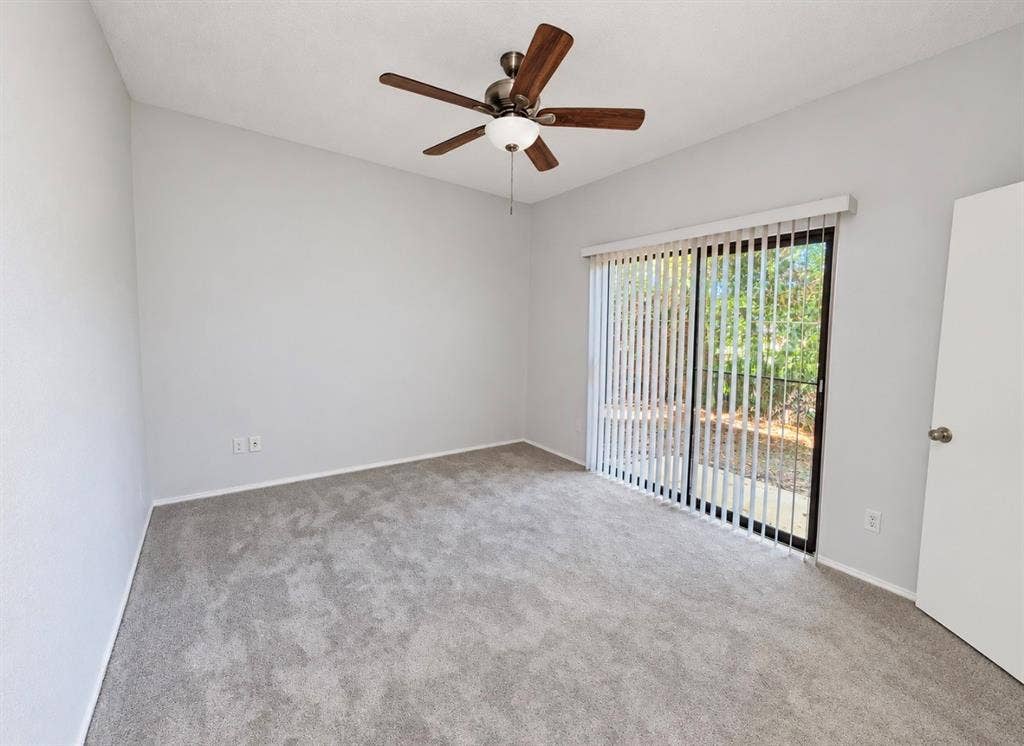 7126 Holly Hill Drive, #108, Dallas, TX 75231 Sliding glass door with vertical blinds, ceiling fan with integrated lighting, and neutral tone carpeting