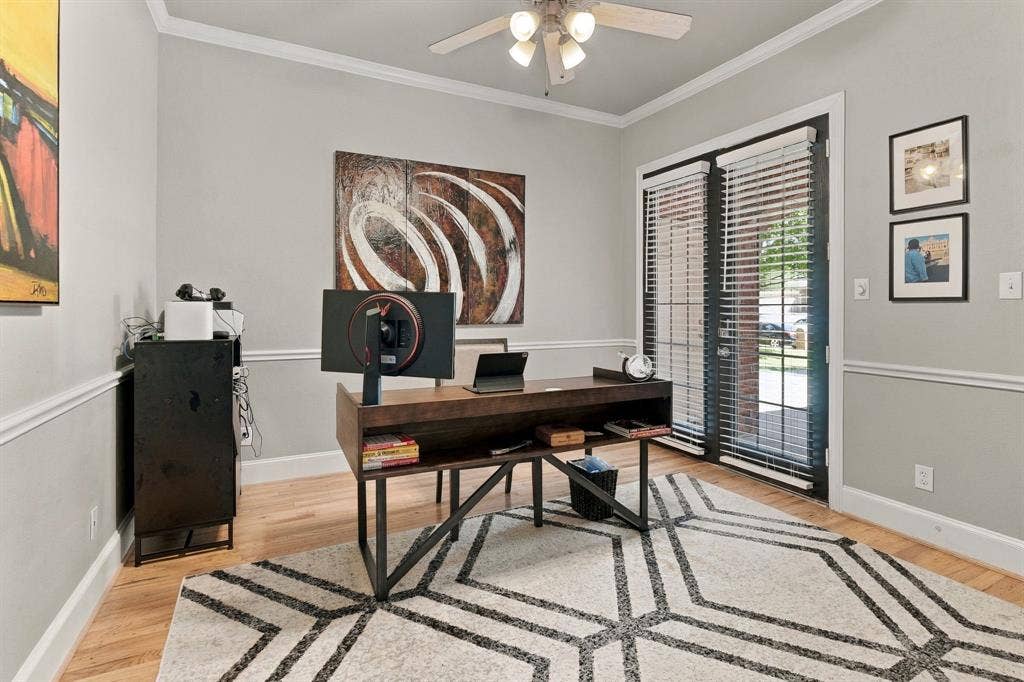 Main-Level Secondary Bedroom / Office | Currently used as a home office, this flexible downstairs bedroom features wood flooring, a ceiling fan and a large window.
