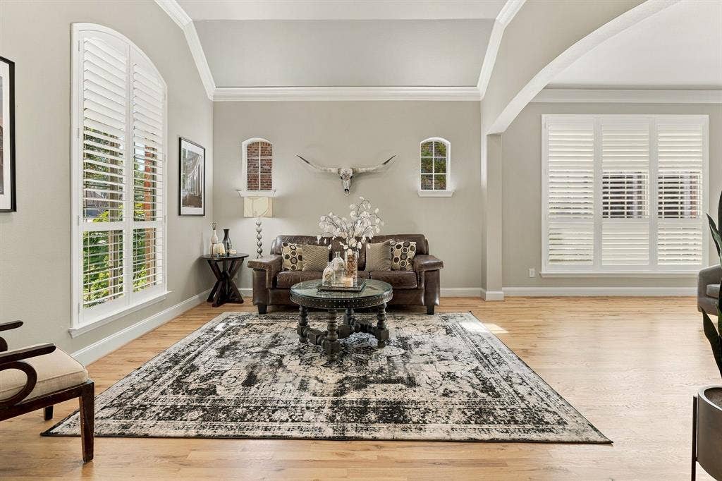 Formal Living Room | Front living space with wood flooring, tall windows, crown molding and an arched opening to the adjacent formal dining area.