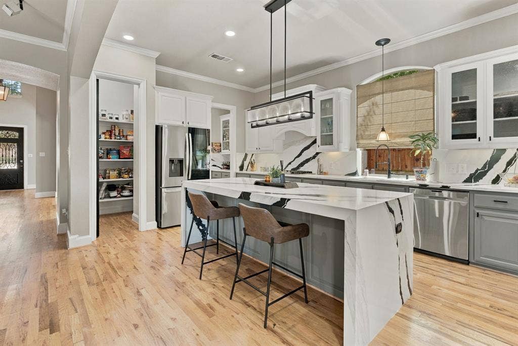 Remodeled Kitchen | Waterfall granite island with seating, pendant lighting, wood flooring and extensive cabinetry anchor the open kitchen.