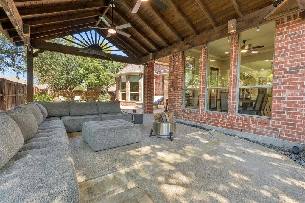 Covered Outdoor Living Area | Wood ceiling, brick columns and a broad patio provide sheltered seating beside the backyard pool.