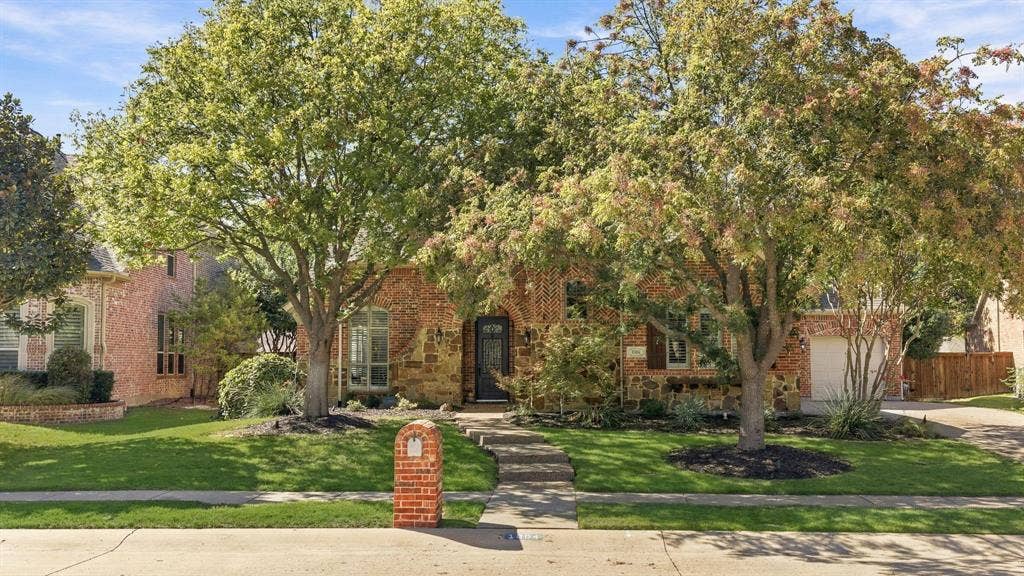 Front Exterior, Daytime | Mature shade trees and landscaped beds frame the front elevation of this Woodhaven II home in Stonebridge Ranch.