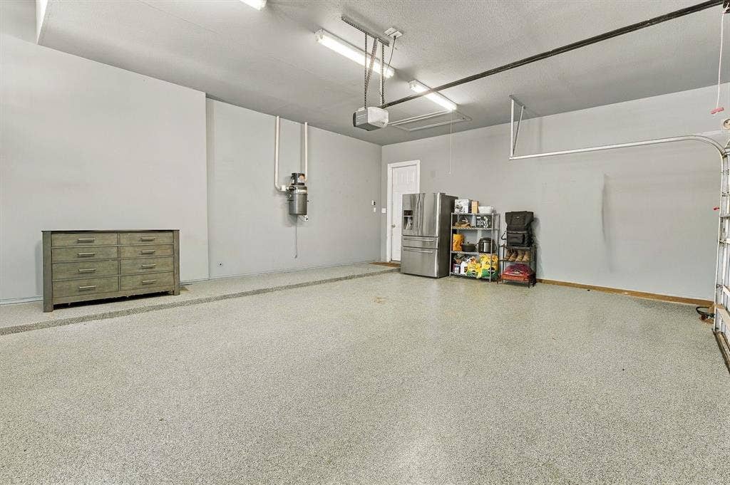 Three-Car Garage | Spacious garage with epoxy-finished floors, overhead lighting and room for vehicles and storage.