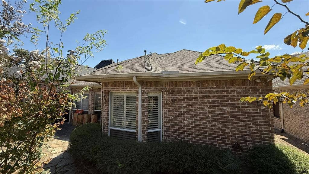 5700 Travis Drive, Frisco, TX 75034 Brick exterior, multiple windows with louvered blinds, shingled roof, rain gutters, and established landscaping