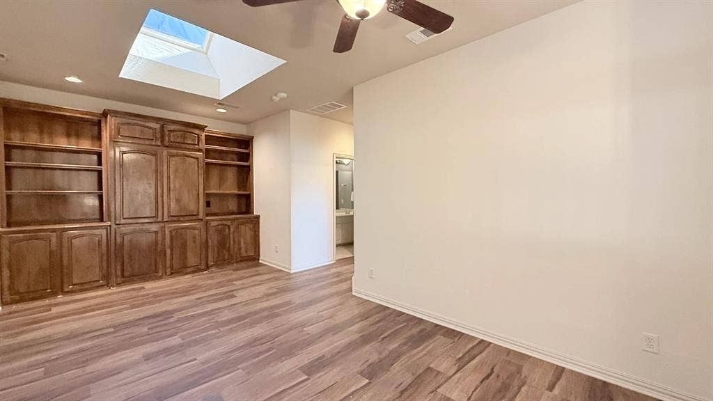 5700 Travis Drive, Frisco, TX 75034 Wood-finish flooring, built-in cabinetry with shelving, recessed lighting, and a skylight
