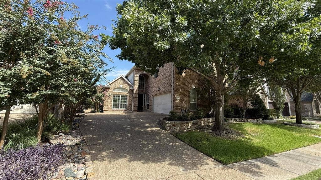5700 Travis Drive, Frisco, TX 75034 Brick facade residence with a two-car garage, arched entry, and a curved driveway
