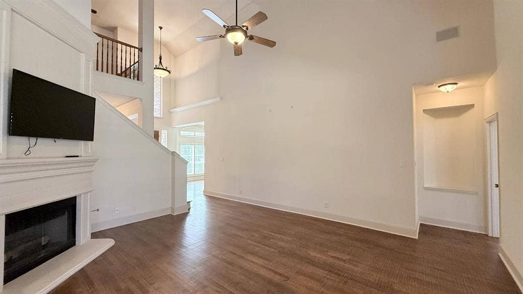 5700 Travis Drive, Frisco, TX 75034 Vaulted ceilings with a ceiling fan, a fireplace with a mantel, wood-finish flooring, and a second-story interior balcony