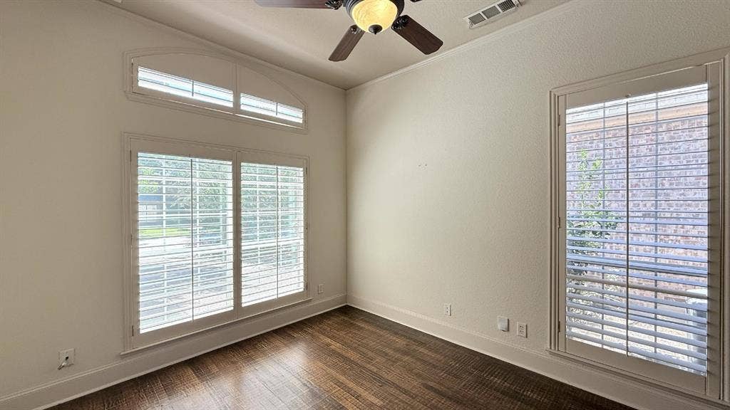 5700 Travis Drive, Frisco, TX 75034 Arched window with plantation shutters, additional window with plantation shutters, wood-finish flooring, and a ceiling fan with light fixture