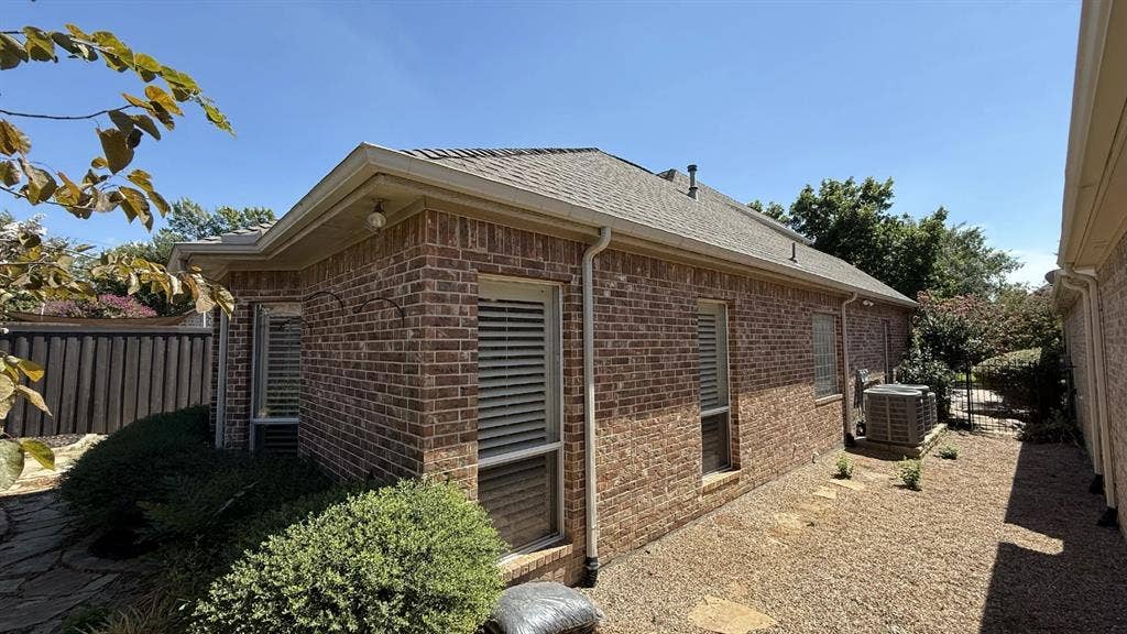 5700 Travis Drive, Frisco, TX 75034 Brick exterior with multiple windows, a sloped roof, and a gravel pathway