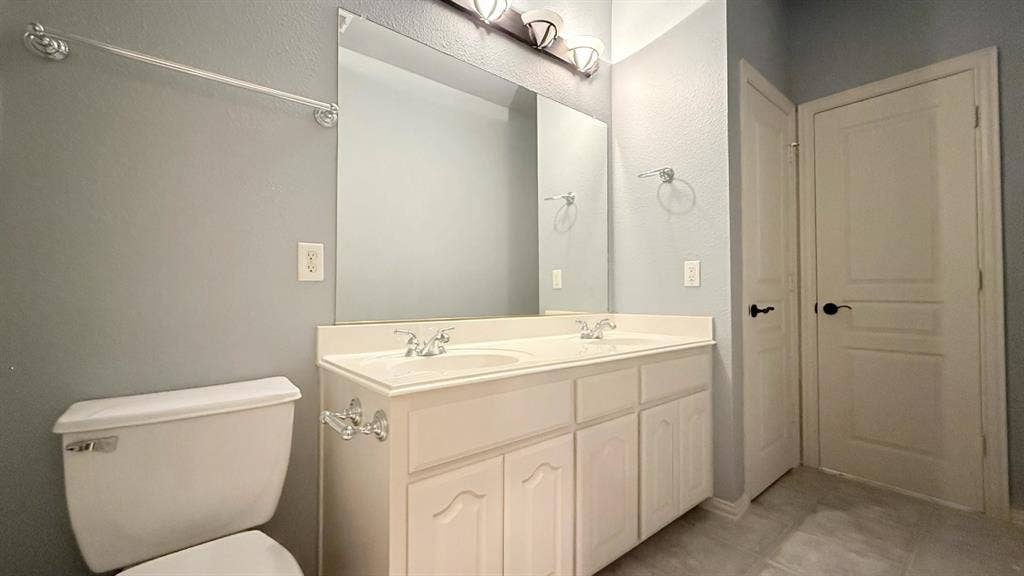 5700 Travis Drive, Frisco, TX 75034 Dual vanity with white cabinetry and integrated sinks, complemented by chrome fixtures