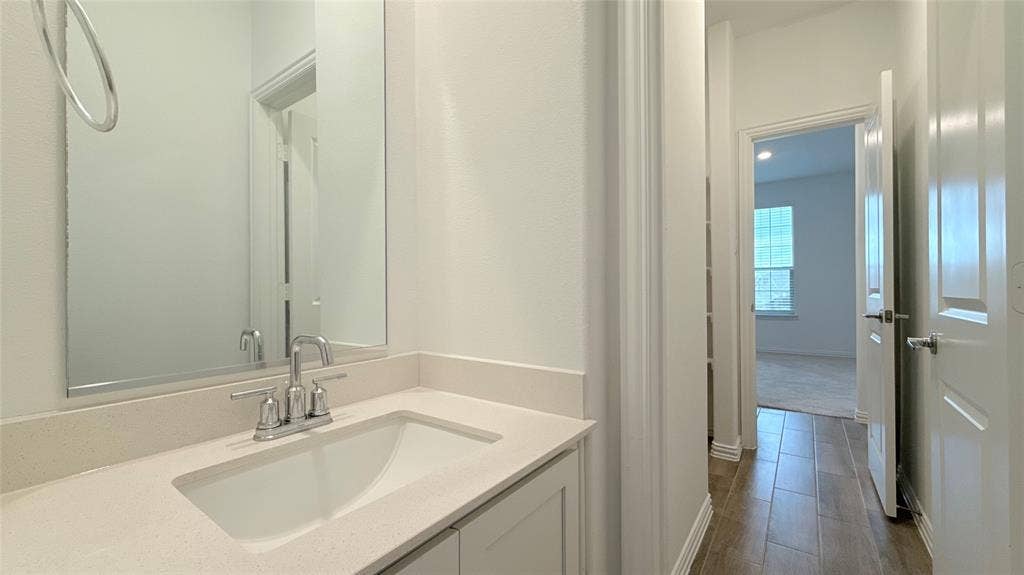 Vanity with integrated sink and chrome faucet, light-toned countertop, and mirror