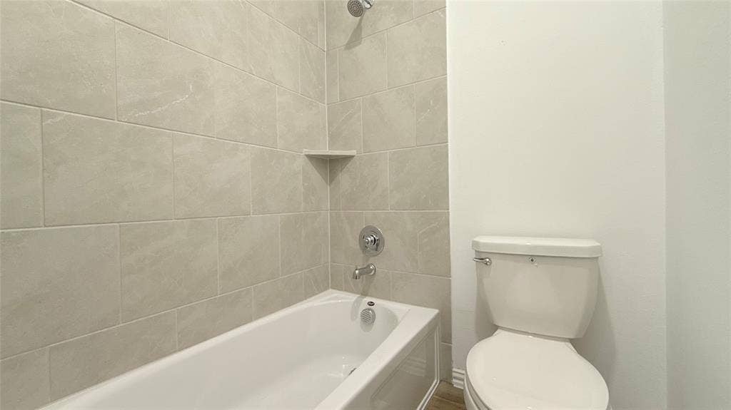 Bathtub with integrated shelving, chrome fixtures, and neutral wall tiling