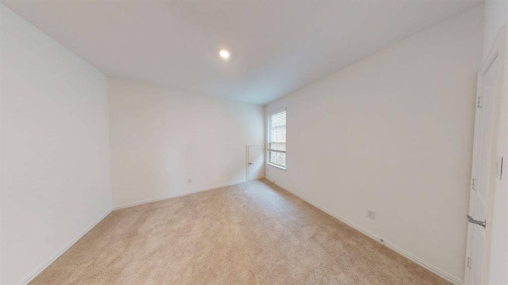 Neutral toned carpeting, recessed ceiling lighting, and a white paneled door