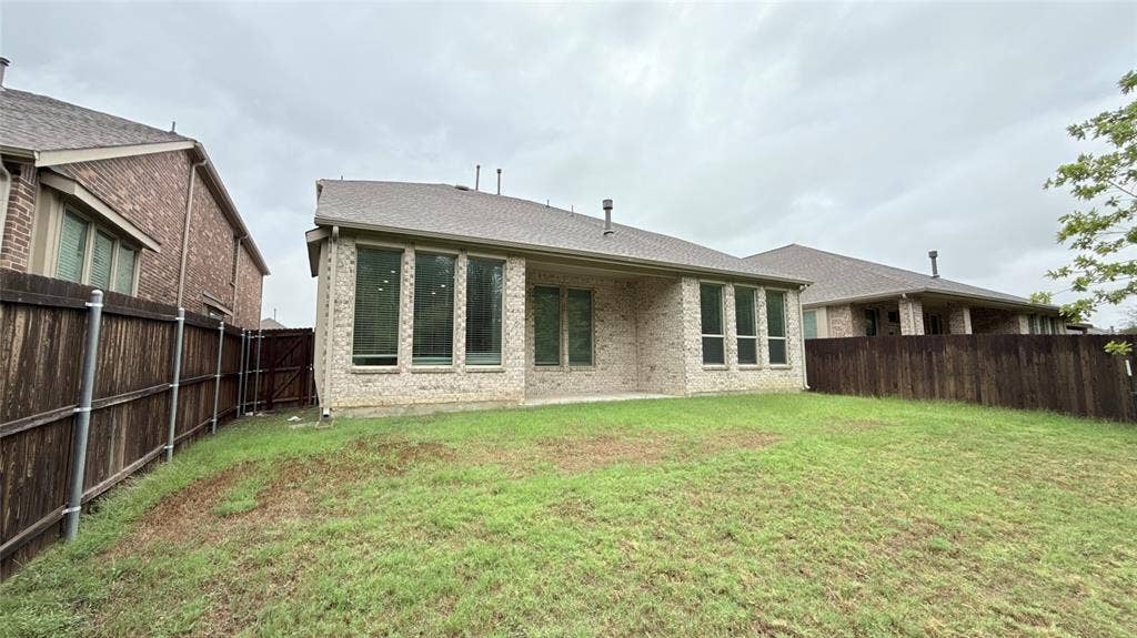 Brick exterior with multiple large windows, a covered patio, and a fenced yard