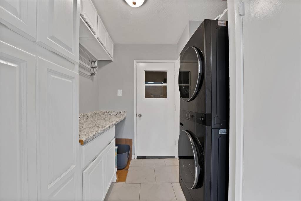 1400 Lorrie Drive, Richardson, TX 75080 Washroom with light tile patterned floors and stacked washer and clothes dryer