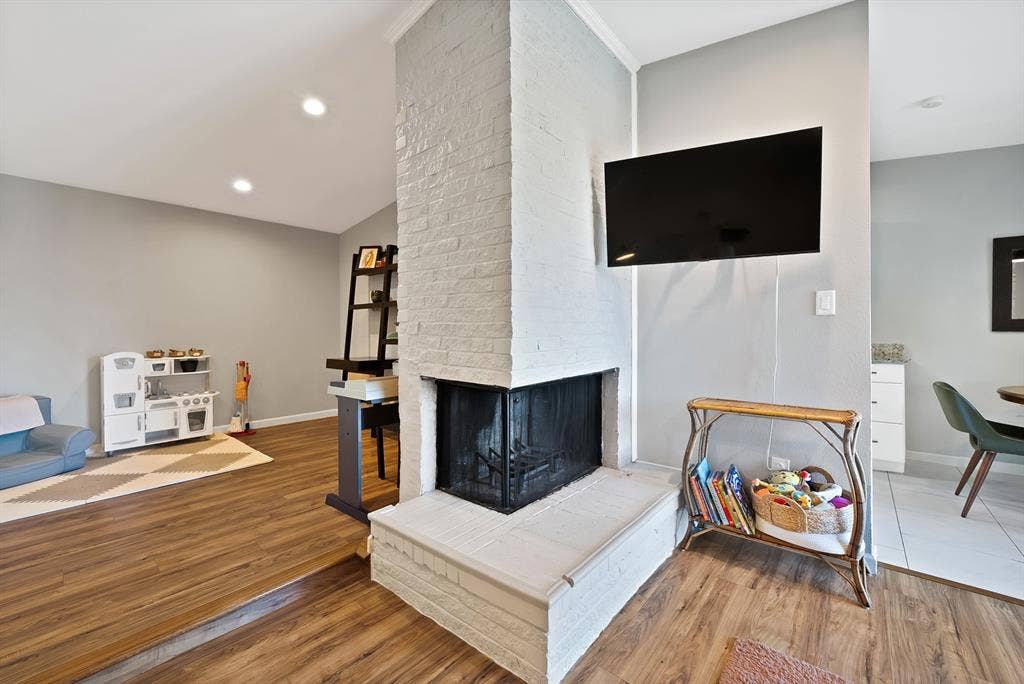 1400 Lorrie Drive, Richardson, TX 75080 Living area with lofted ceiling, wood finished floors, a brick fireplace, and recessed lighting