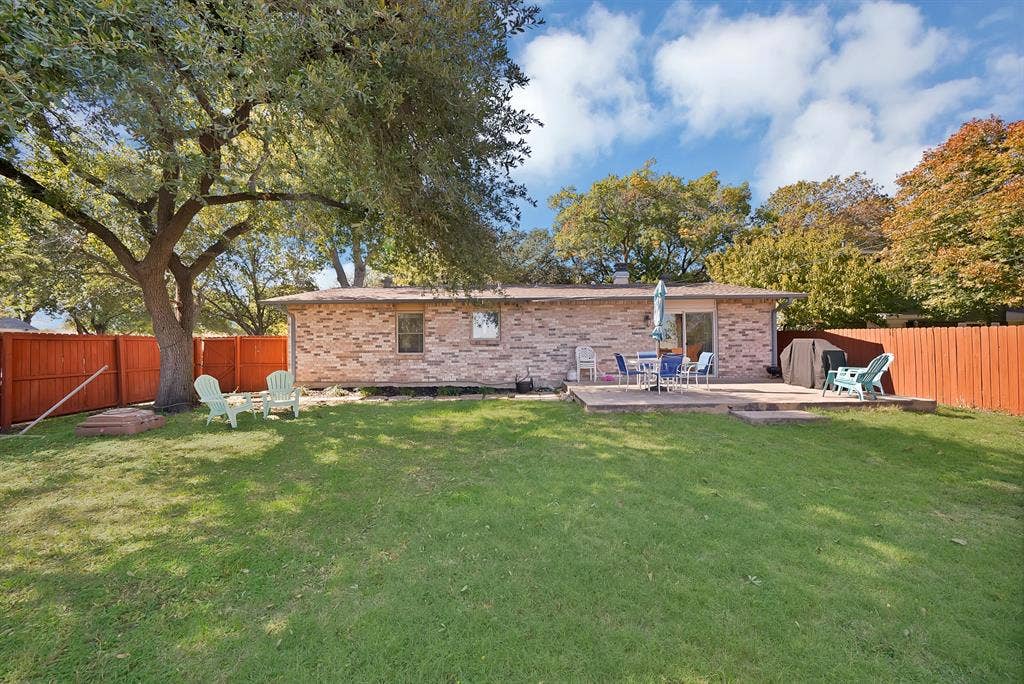 1400 Lorrie Drive, Richardson, TX 75080 Back of house with a fenced backyard, brick siding, and a wooden deck