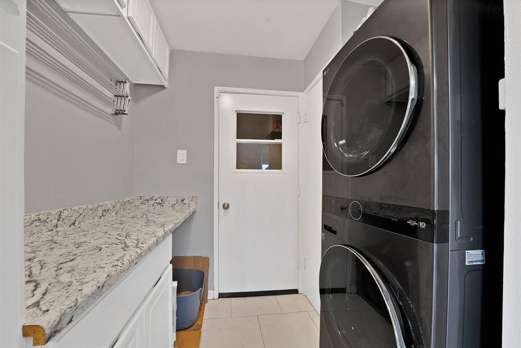 1400 Lorrie Drive, Richardson, TX 75080 Laundry room featuring light tile patterned floors and stacked washer and clothes dryer