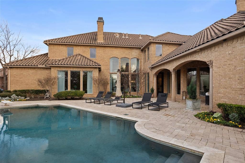 6300 Caroline Drive, Frisco, TX 75034 Exterior featuring a swimming pool, spacious patio, brick facade, arched entryways, and multiple windows