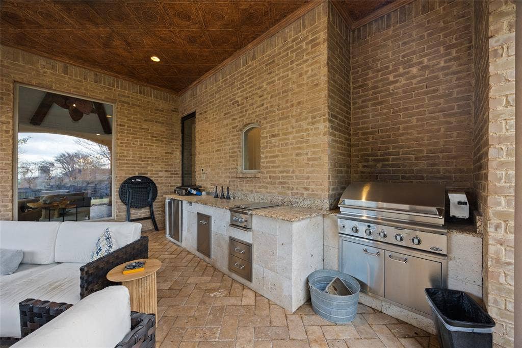 6300 Caroline Drive, Frisco, TX 75034 Outdoor kitchen featuring a built-in stainless steel grill, integrated sink, and stone countertops