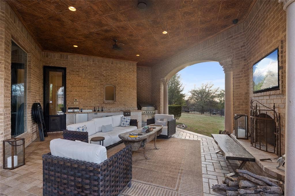 6300 Caroline Drive, Frisco, TX 75034 Expansive covered patio featuring a brick exterior, recessed lighting, and a built-in outdoor kitchen with stainless steel appliances