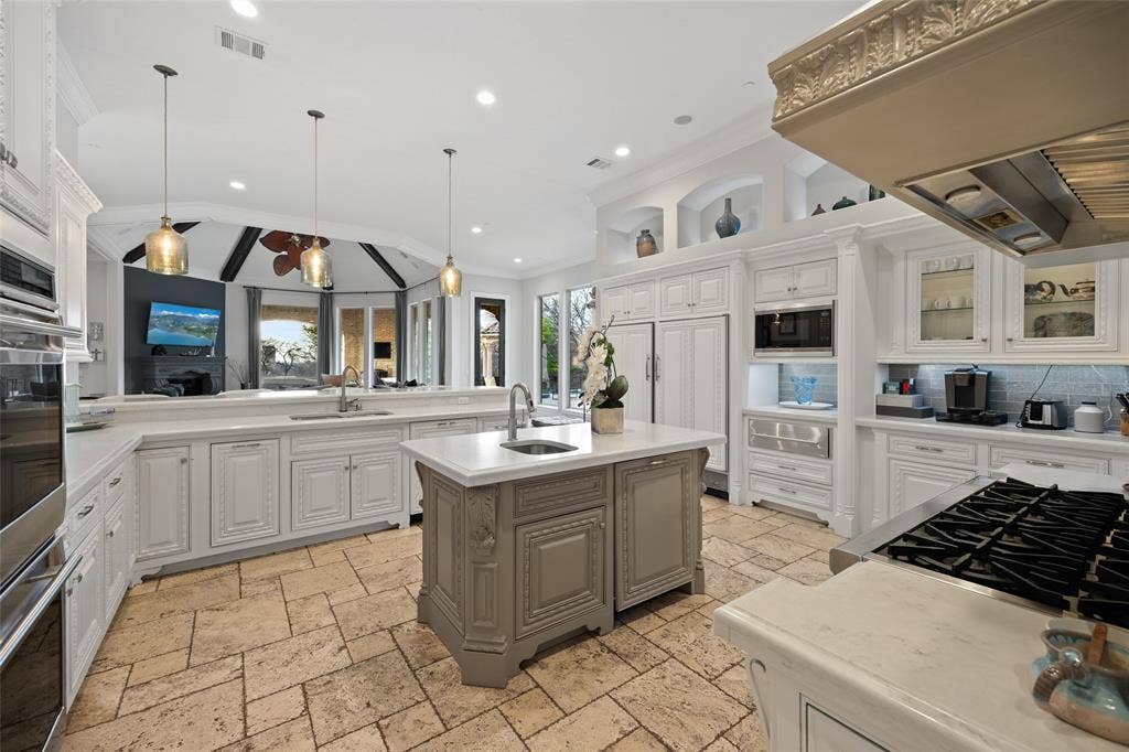 6300 Caroline Drive, Frisco, TX 75034 Gourmet kitchen featuring stone tile flooring, a large center island with a sink, white cabinetry, integrated appliances, and recessed lighting