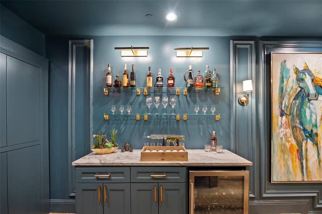 6300 Caroline Drive, Frisco, TX 75034 Built-in wet bar featuring a stone countertop, under-counter beverage refrigerator, custom cabinetry with brass hardware, and glass shelving