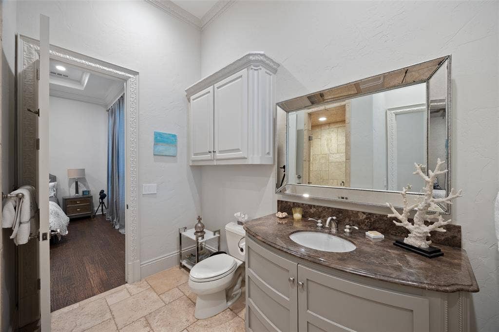 6300 Caroline Drive, Frisco, TX 75034 Curved vanity with an undermount sink, stone countertop, and custom cabinetry