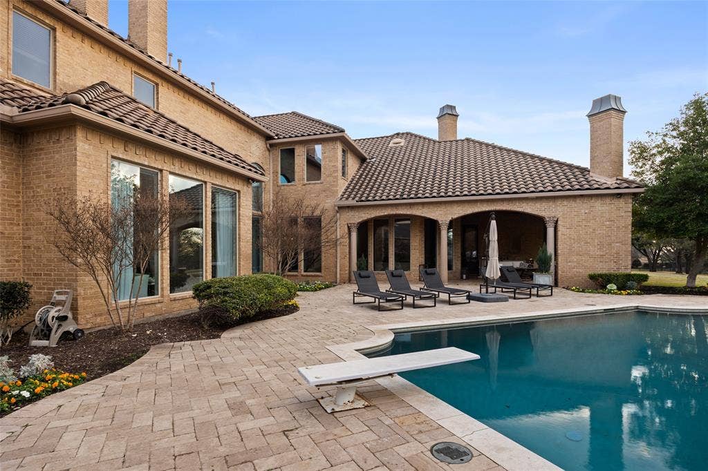 6300 Caroline Drive, Frisco, TX 75034 Brick exterior with arched covered patio, expansive pool with diving board, and paver patio