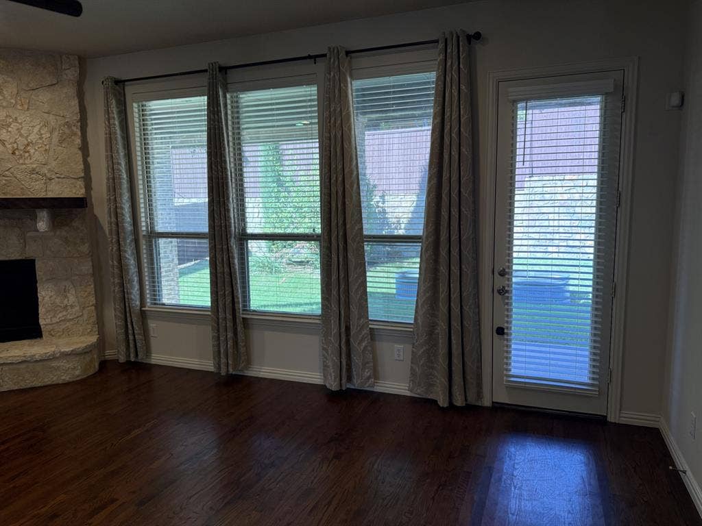 13721 Vera Cruz Road, Frisco, TX 75035 Hardwood flooring, stone-clad fireplace with wood mantel, multiple windows, and a glass-paneled door