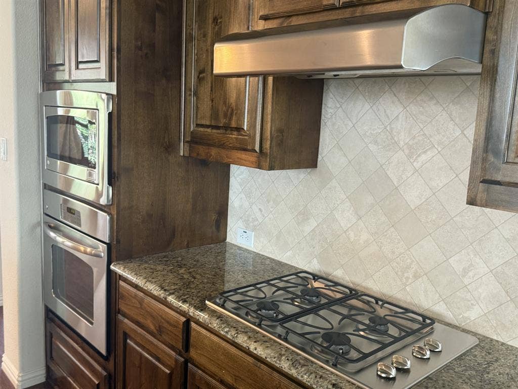 13721 Vera Cruz Road, Frisco, TX 75035 Stainless steel built-in microwave and oven, gas cooktop, granite-finish countertops, and wood-finish cabinetry
