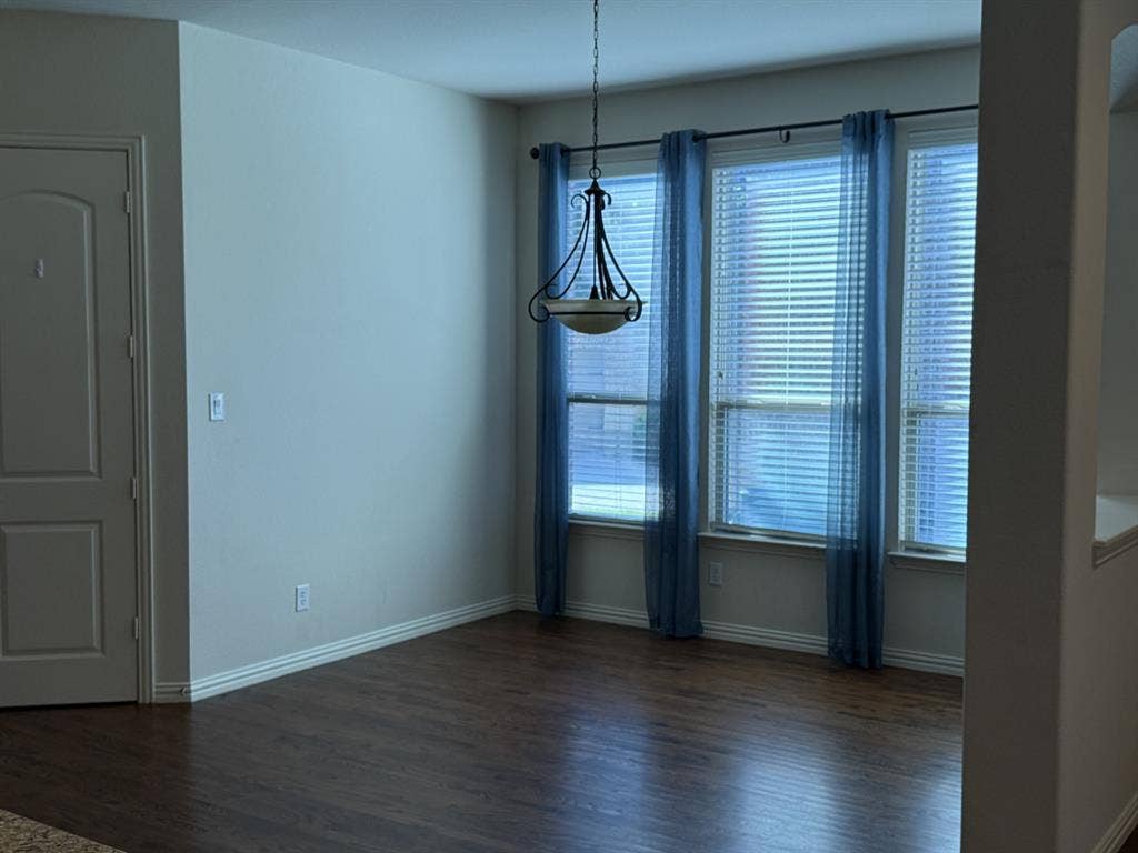13721 Vera Cruz Road, Frisco, TX 75035 Hardwood-finish flooring, three large windows, and a hanging light fixture create an inviting atmosphere