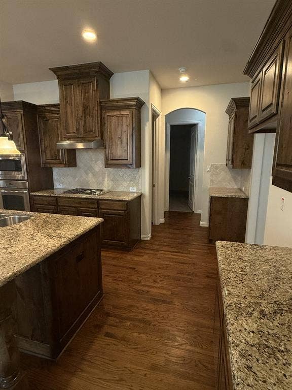 13721 Vera Cruz Road, Frisco, TX 75035 Wood-finish flooring, dark wood cabinetry, light-toned countertops, and a tile backsplash