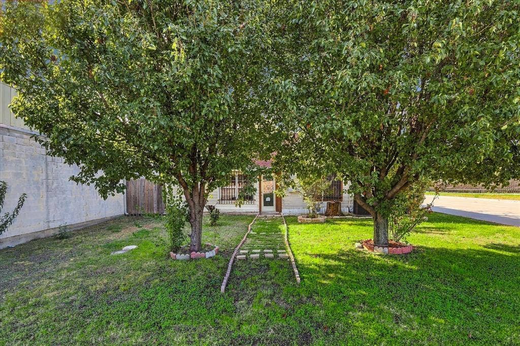 Front yard featuring mature trees, a stone-paved walkway, and a masonry exterior