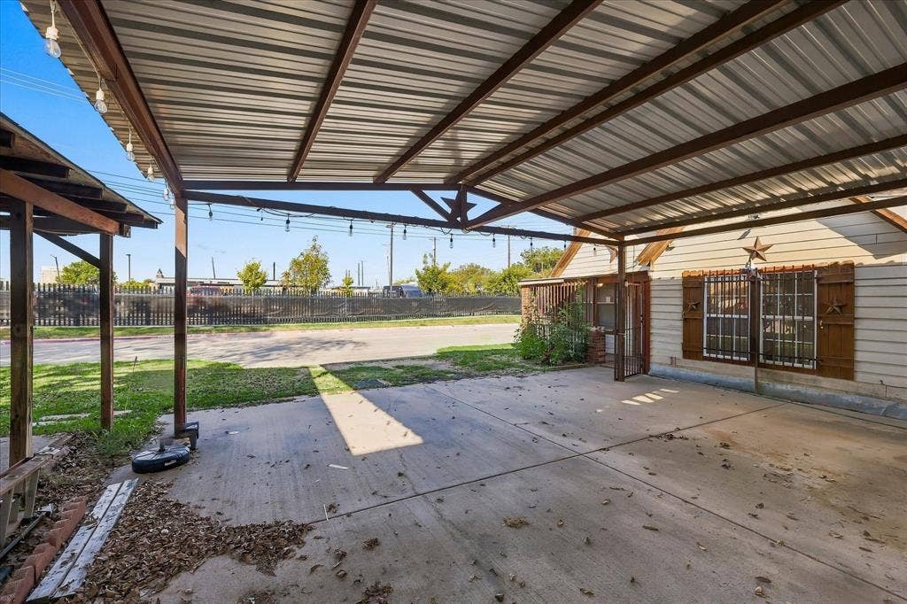 Covered carport with metal roofing, structural steel framing, concrete flooring, and exterior siding