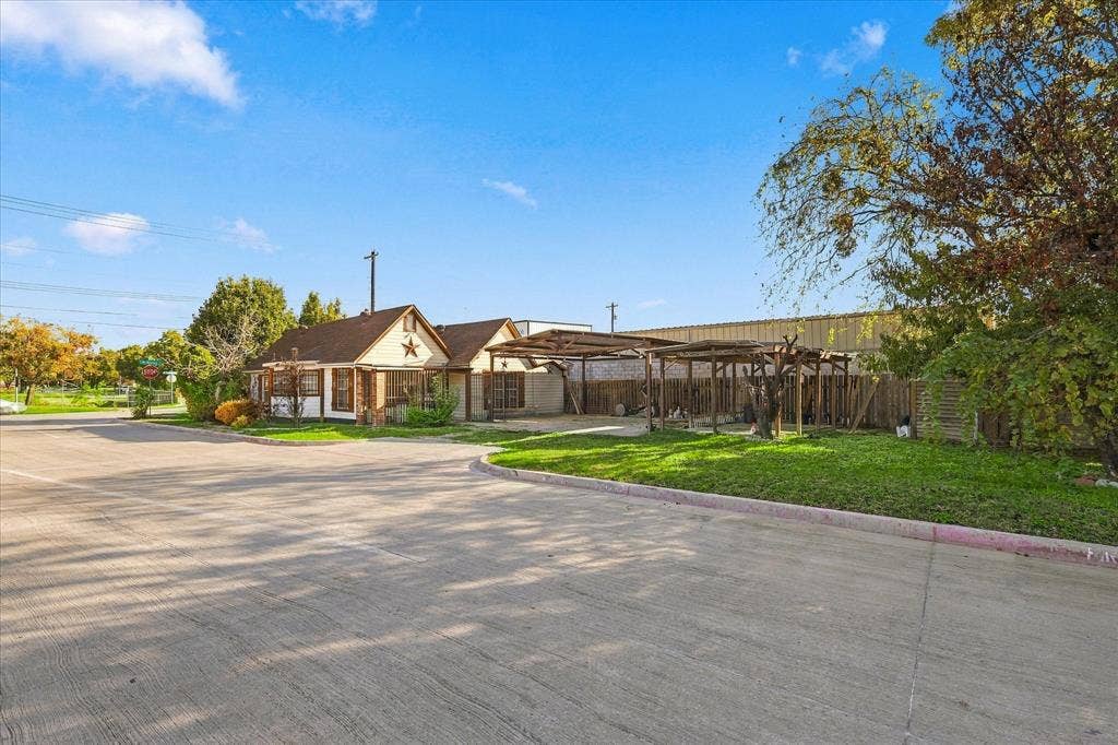 Single-story exterior featuring a brick facade, decorative star accent, asphalt shingle roofing, and an attached multi-bay open-air carport