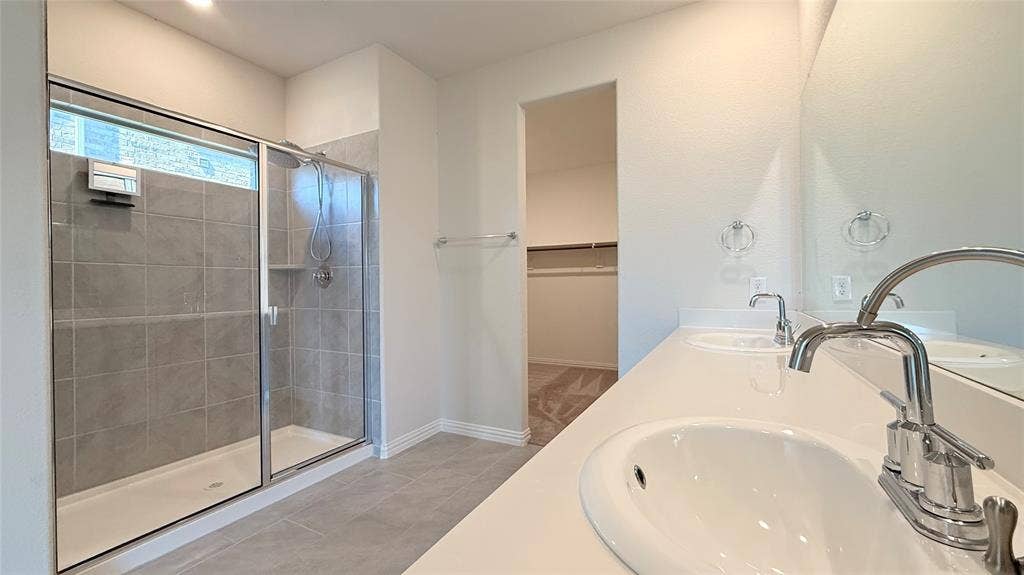 531 Deer Canyon Way, Princeton, TX 75407 Dual vanity with integrated sinks, expansive counter space, large mirror, glass-enclosed shower, and tiled flooring