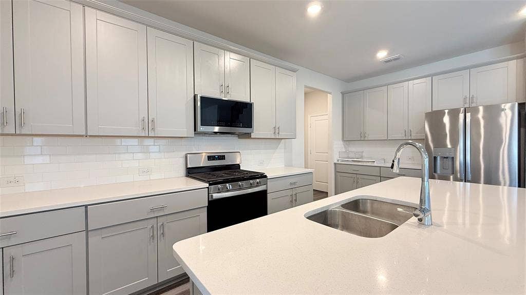 531 Deer Canyon Way, Princeton, TX 75407 White subway tile backsplash, stainless steel appliances, dual basin sink, light-toned cabinetry, and recessed lighting