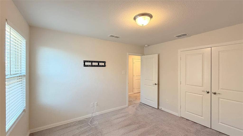 531 Deer Canyon Way, Princeton, TX 75407 Carpeted room featuring a ceiling-mounted light fixture, louvered window blinds, and paneled doors with satin nickel hardware