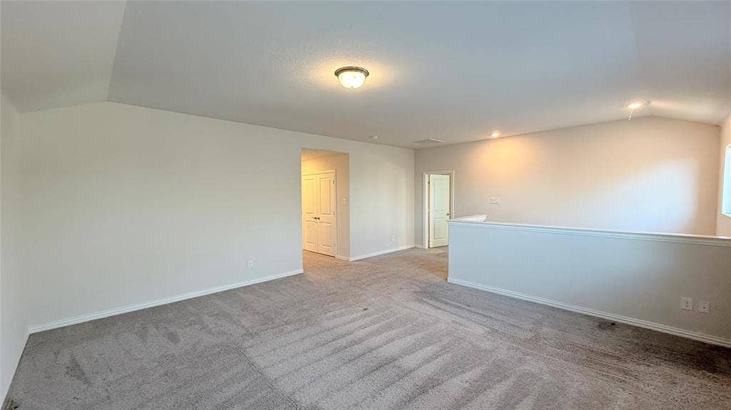 531 Deer Canyon Way, Princeton, TX 75407 Vaulted ceiling, recessed lighting, neutral tone carpet, half-wall partition, and warm wall color
