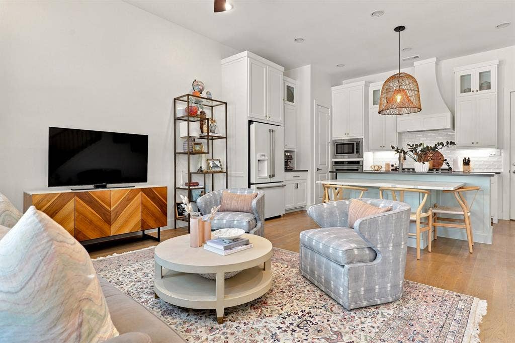 1137 Manderly Court, Dallas, TX 75204 Hardwood flooring throughout, white cabinetry with integrated appliances, kitchen island with seating, built-in shelving, and recessed lighting