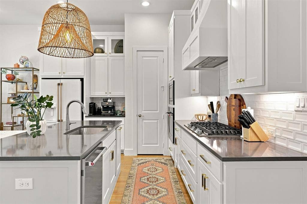 1137 Manderly Court, Dallas, TX 75204 White shaker cabinetry, dark countertops, hardwood flooring, built-in stainless steel appliances, and a gas cooktop