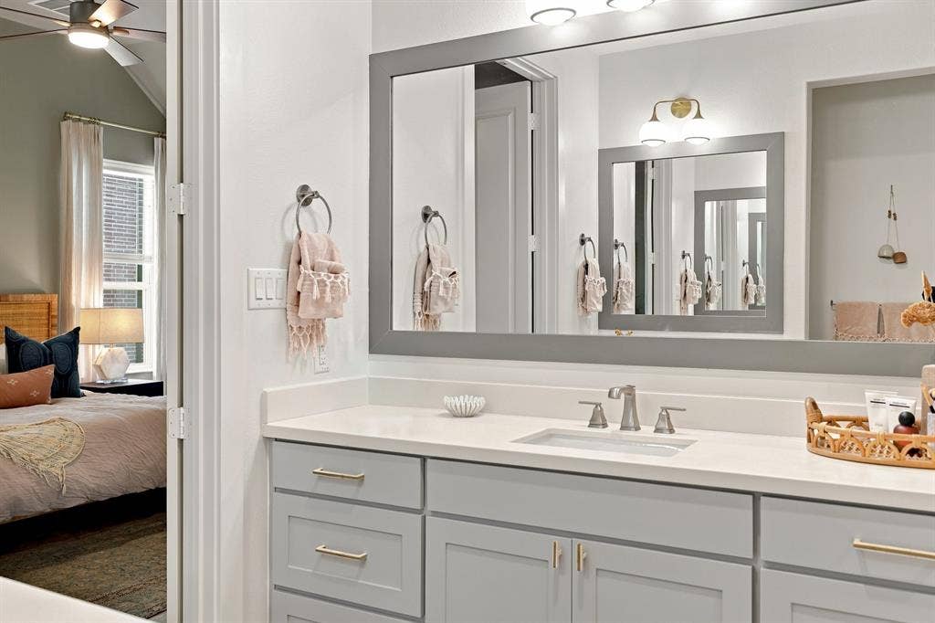 1137 Manderly Court, Dallas, TX 75204 Bathroom vanity with light gray cabinetry, brushed nickel fixtures, a single basin sink, and a large wall-mounted mirror