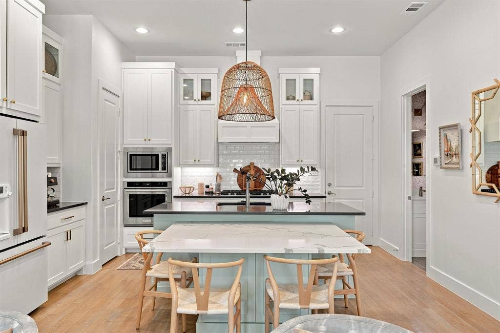 1137 Manderly Court, Dallas, TX 75204 Kitchen featuring light wood-finish flooring, white cabinetry with gold-tone hardware, a light blue island with a white countertop, and stainless steel appliances