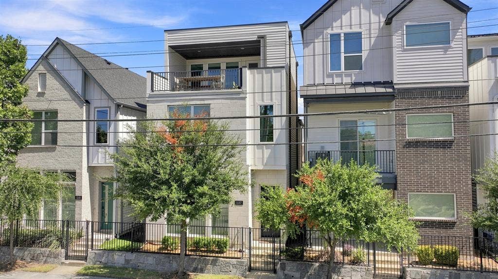 1137 Manderly Court, Dallas, TX 75204 Modern exterior featuring a prominent balcony with black railings, vertical siding accents, and a grey brick facade