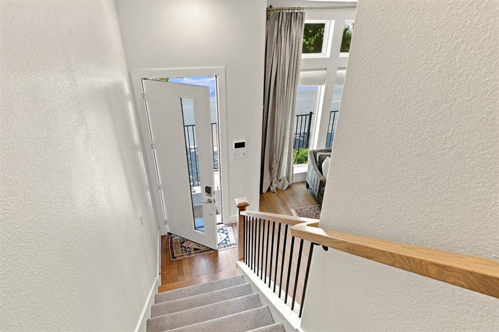 1137 Manderly Court, Dallas, TX 75204 Contemporary white entry door with glass inserts, wood-finish flooring, staircase with carpeted treads, and a natural wood handrail with black metal spindles