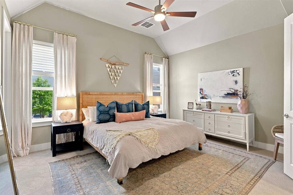 1137 Manderly Court, Dallas, TX 75204 Vaulted ceiling with a ceiling fan, two windows, carpet flooring, wood-finish bed frame, and a built-in dresser